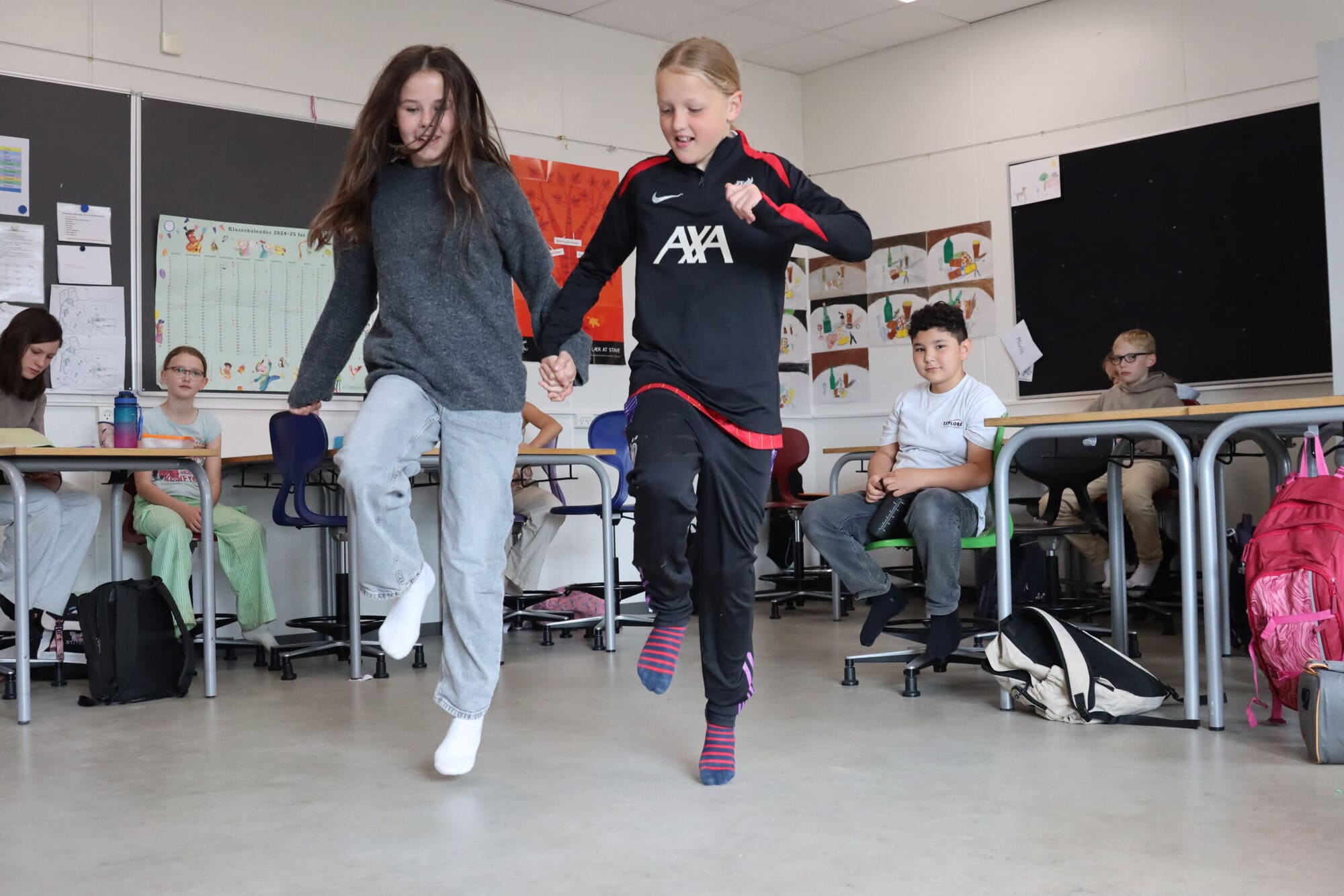 To børn der løber med hinanden i hånden i et klaasselokale