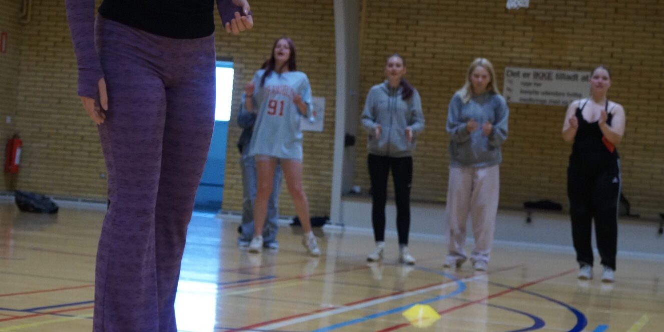 Pige står i en hal og kaster med ærteposer